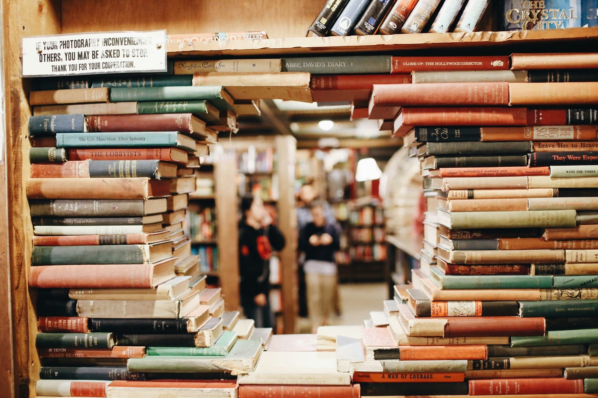 A shelf of books, arranged to create a circular window into the bookstore beyond.