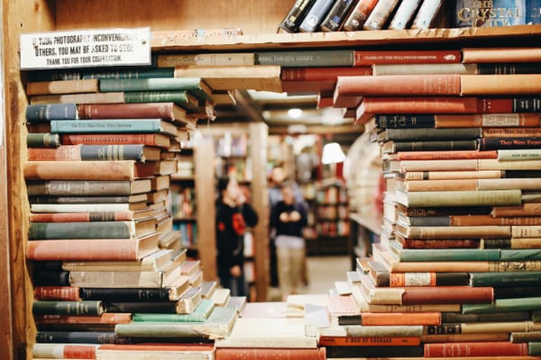 A shelf of books, arranged to create a circular window into the bookstore beyond.